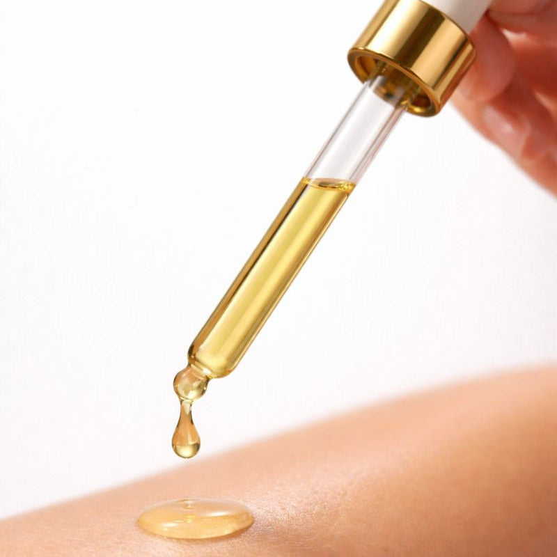 Gold dropper with liquid being applied to skin